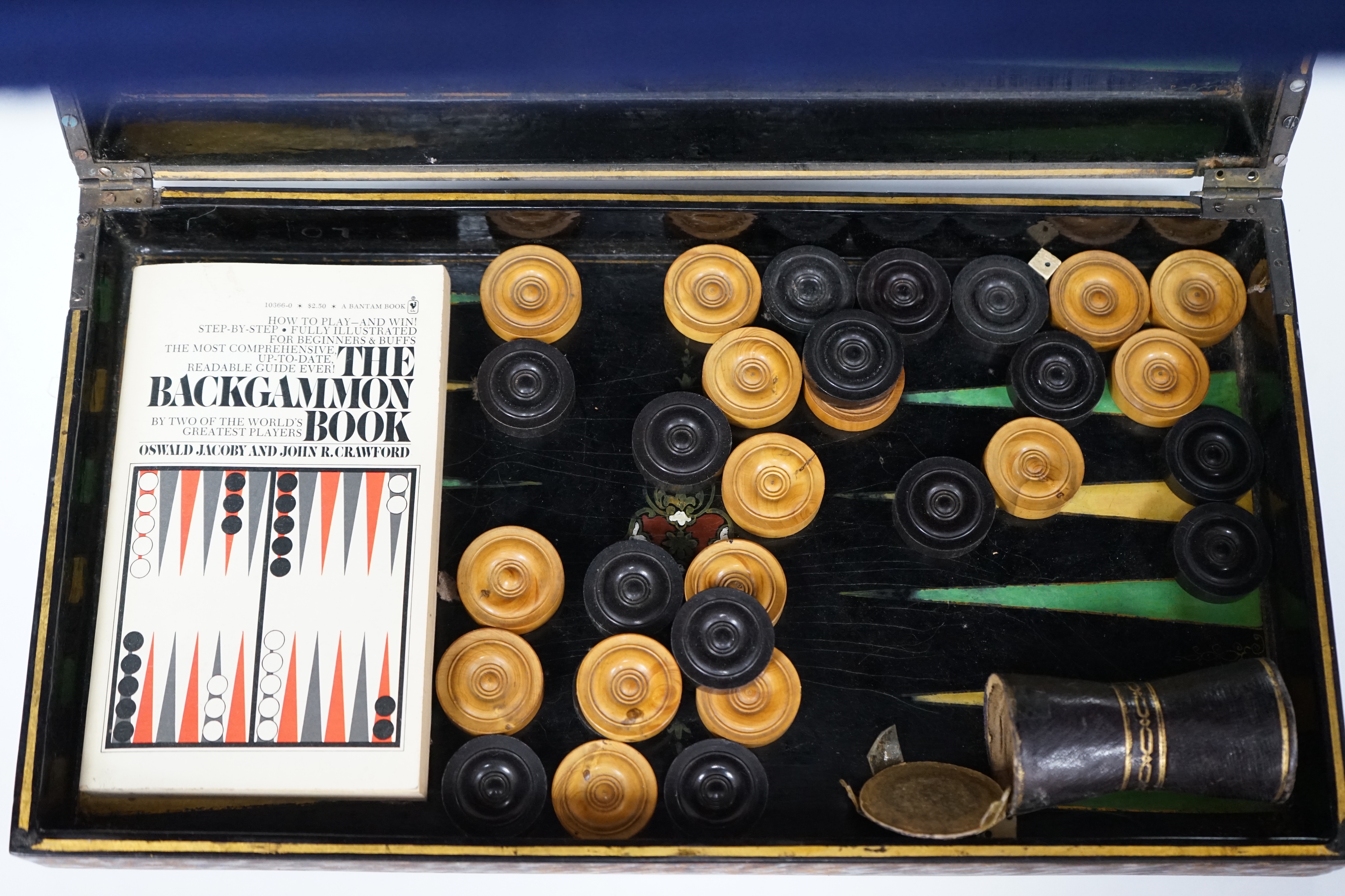 A 19th century papier maché folding games board for chess and backgammon, containing a wooden draughts set etc. with gilt decoration, 41 x 45cm unfolded